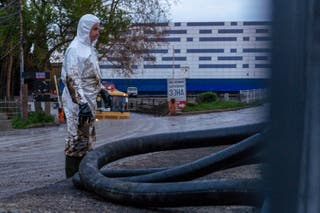 A worker stands next to a hose as he cleans the river of petroleum products following a spill caused by a recent drone attack on the Tuapse oil refinery in Tuapse, Krasnodar region